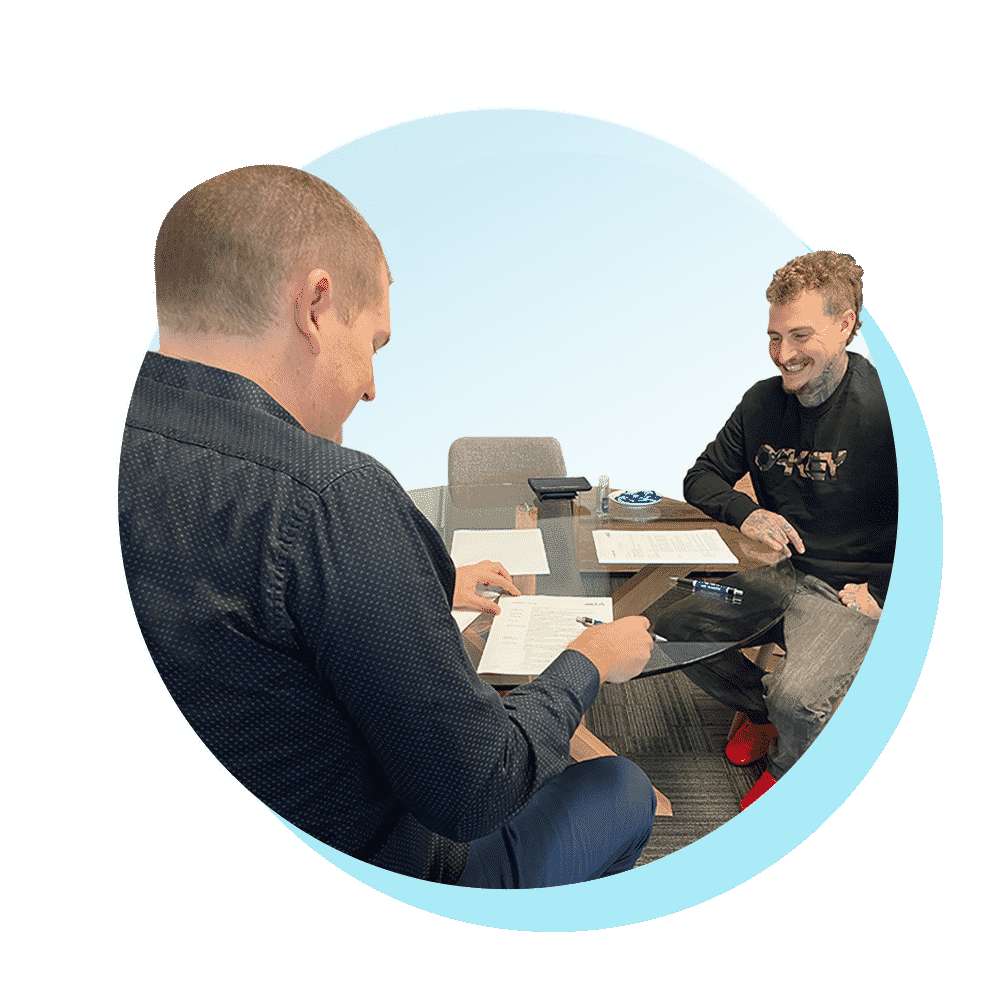 A happy first home buyer signing his finance loan application with Mike Mackenzie